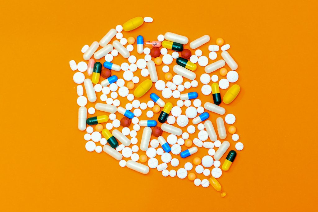 Das Bild zeigt verschiedene Tabletten auf einem orangefarbenen Hintergrund.