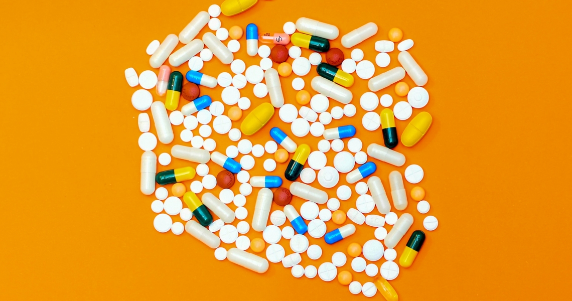 Das Bild zeigt verschiedene Tabletten auf einem orangefarbenen Hintergrund.