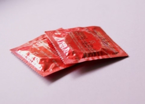 Die Abbildung zeigt zwei einzelne Kondome, in einer roten Verpackung. 