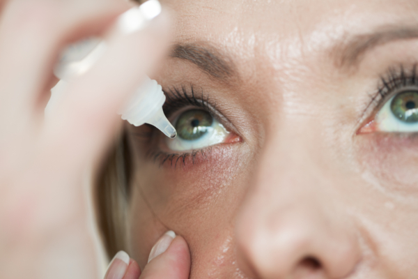 Das Bild zeigt eine Frau, die Augentropfen in ihr Auge tropft. 