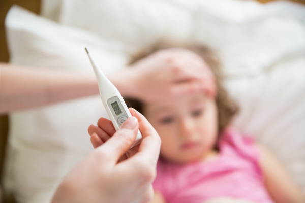 Das Bild zeigt ein Kind mit Fieber und eine Fieberthermometer.