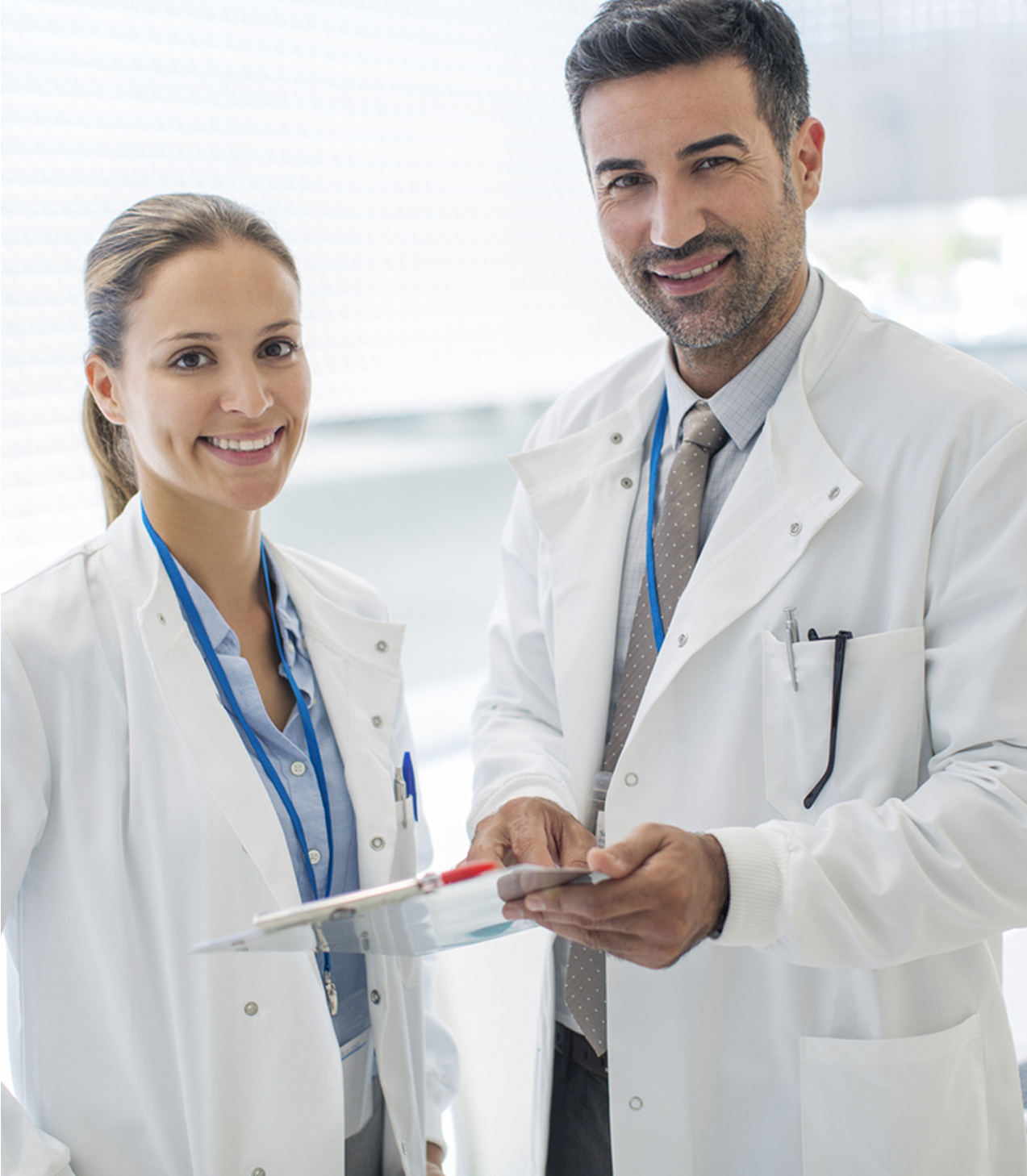 Zwei Ärzte im Gespräch über medizinische Unterlagen in einem hellen Krankenhausflur.